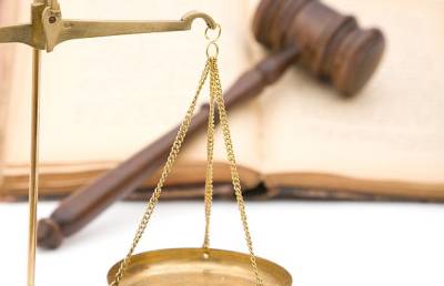 image of a scale with a gavel on top of an open book in the background