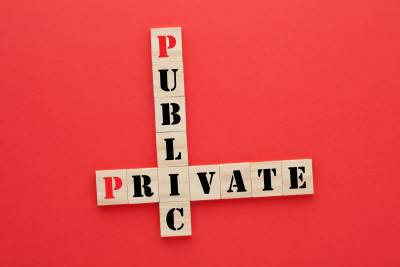 Image or scrabble letters spelling public and private intersecting on a red background.