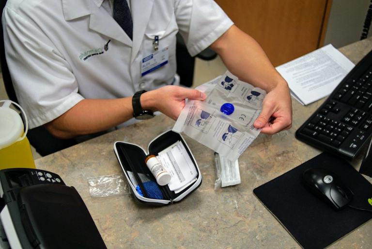 Image of a healthcare worker opening up the instruction sheet for naloxone