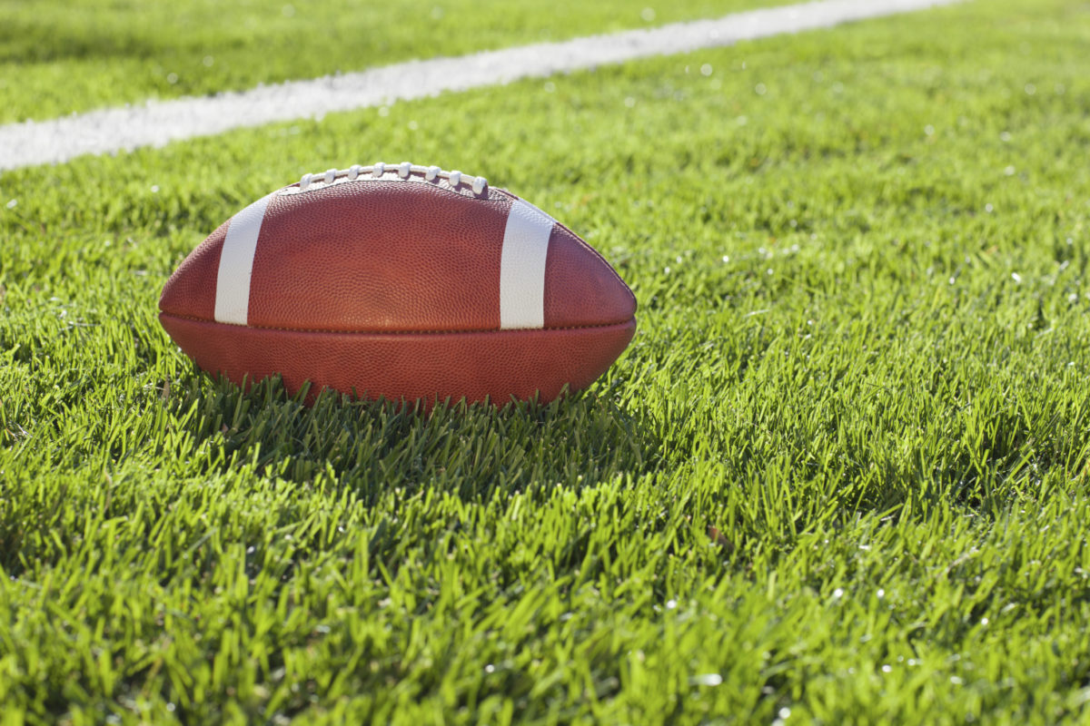 College football on grass field in afternoon sunlight