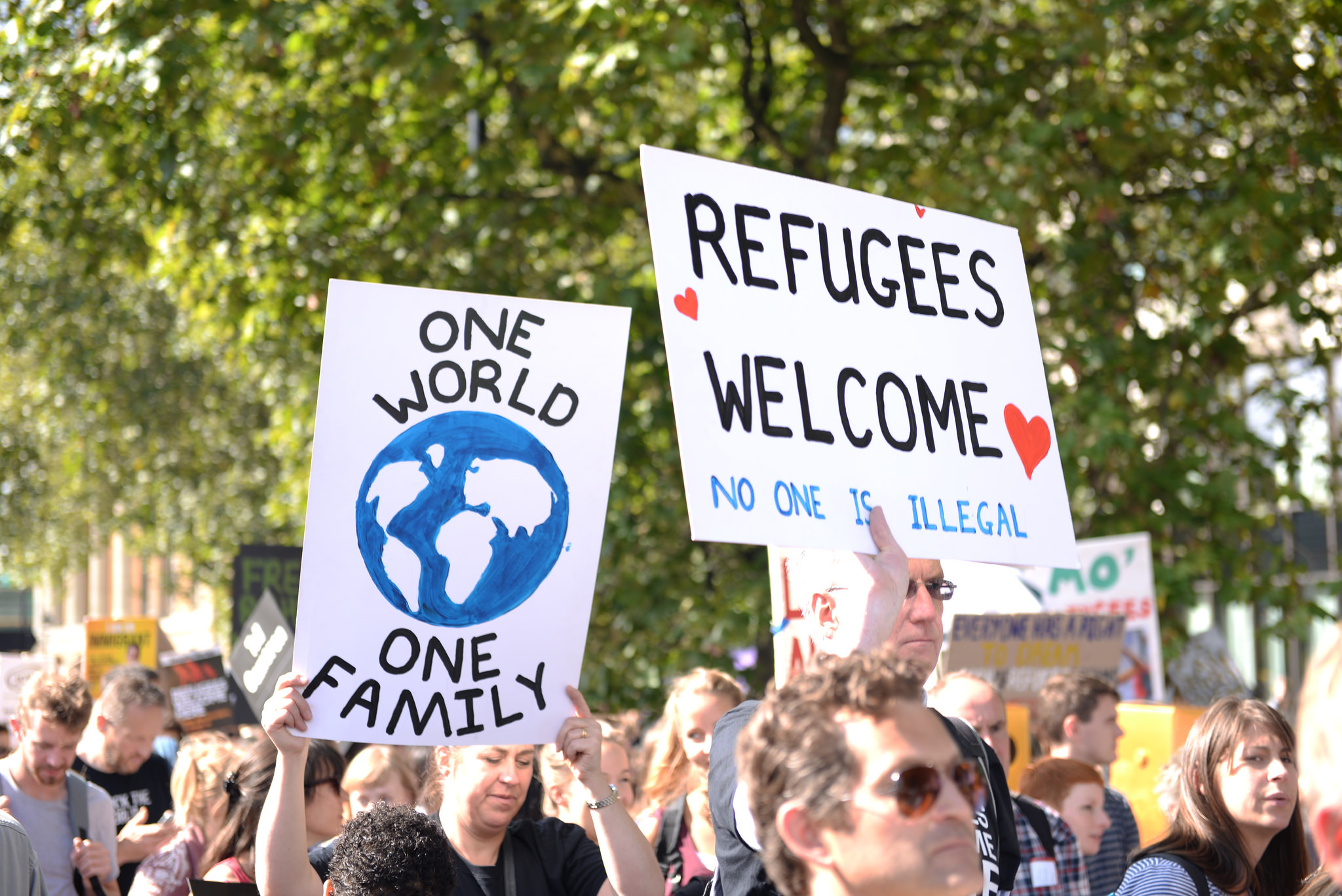 protesters carry signs that say "refugees welcome" in