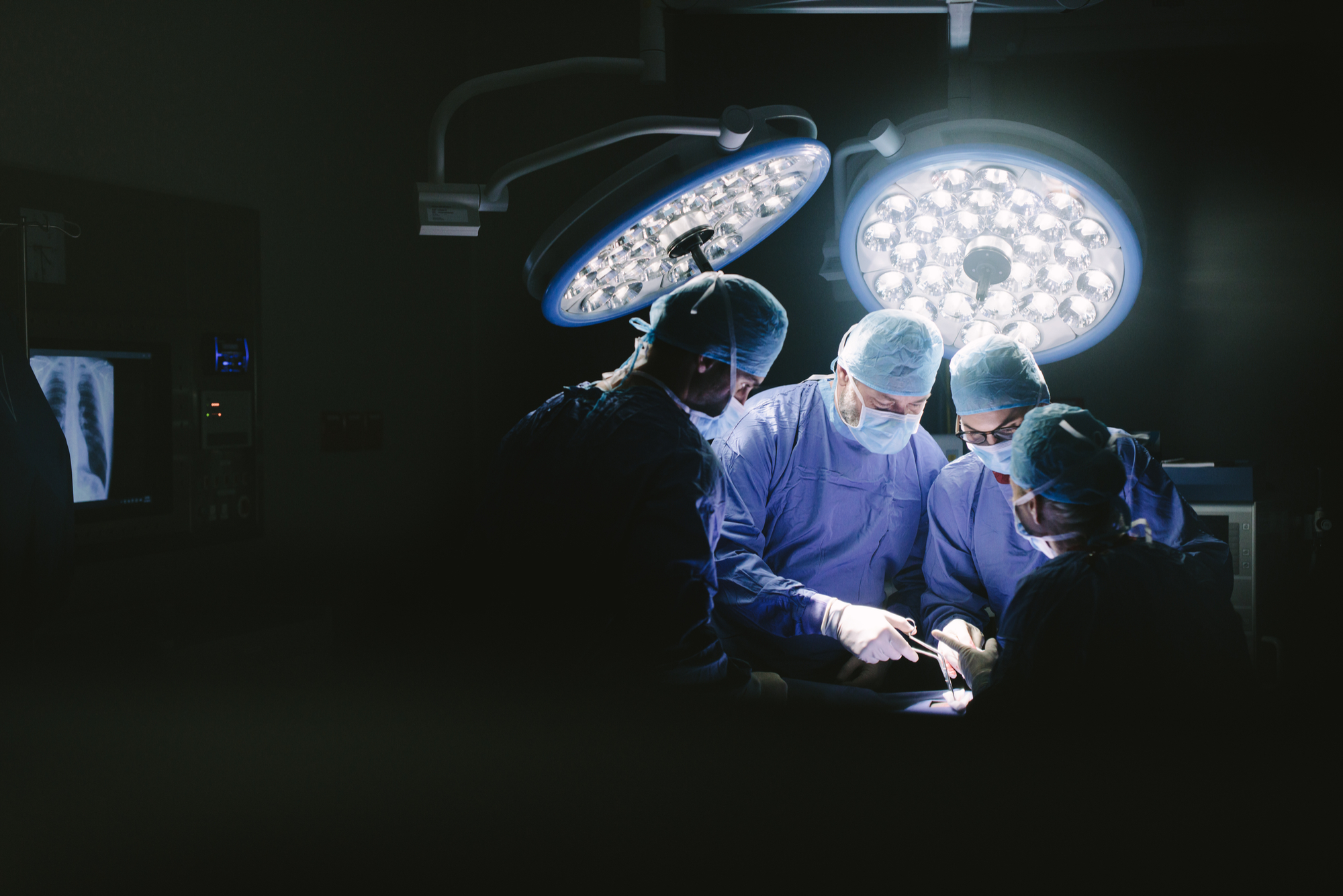 A group of surgeons perform an operation in a hospital operating theatre.