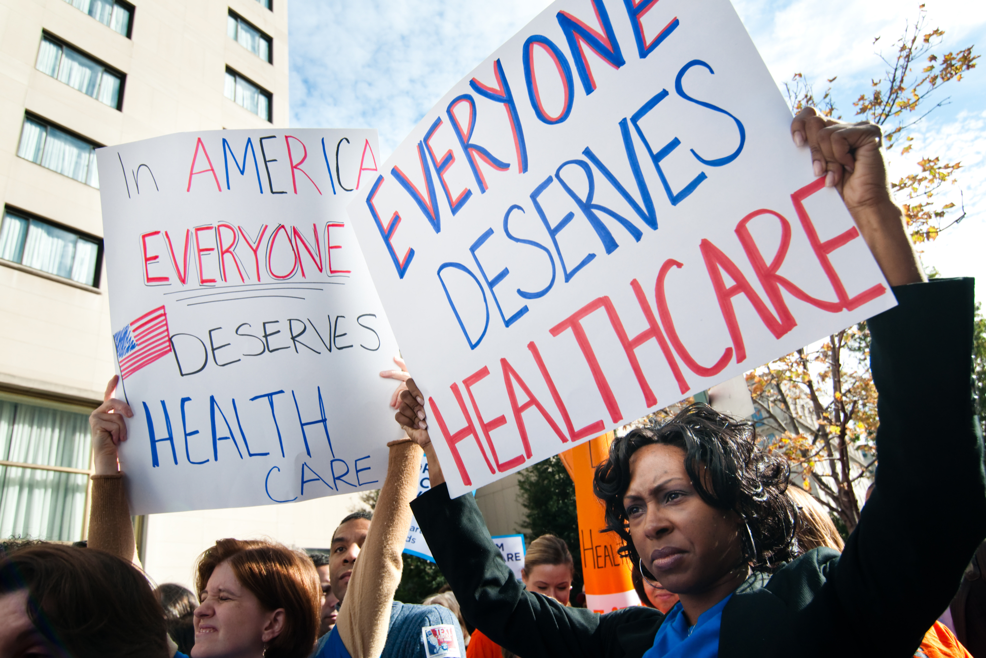 Protesters hold up signs that read "everyone deserves healthcare"