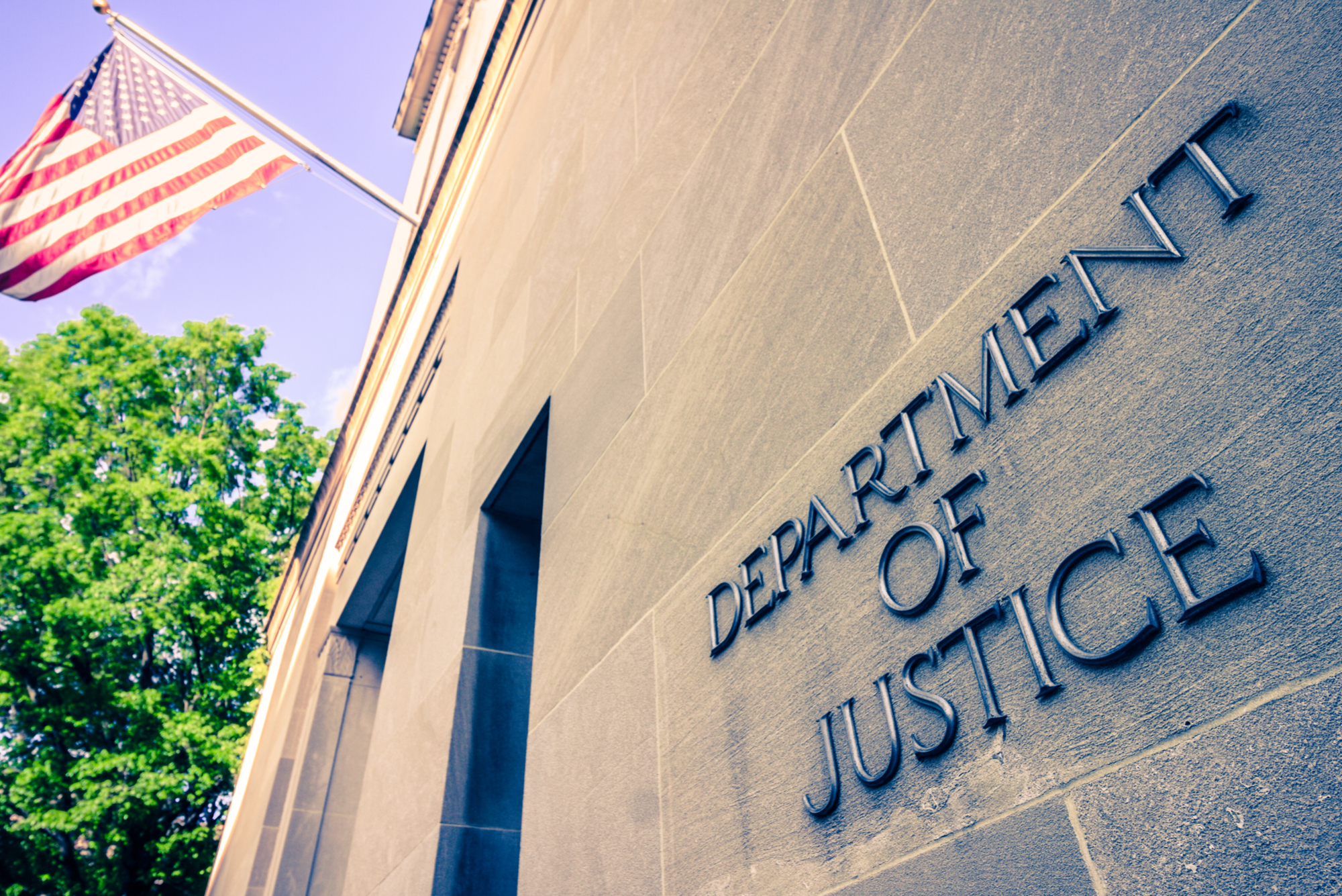 Image of the Department of Justice building with a U.S. flag hanging from it