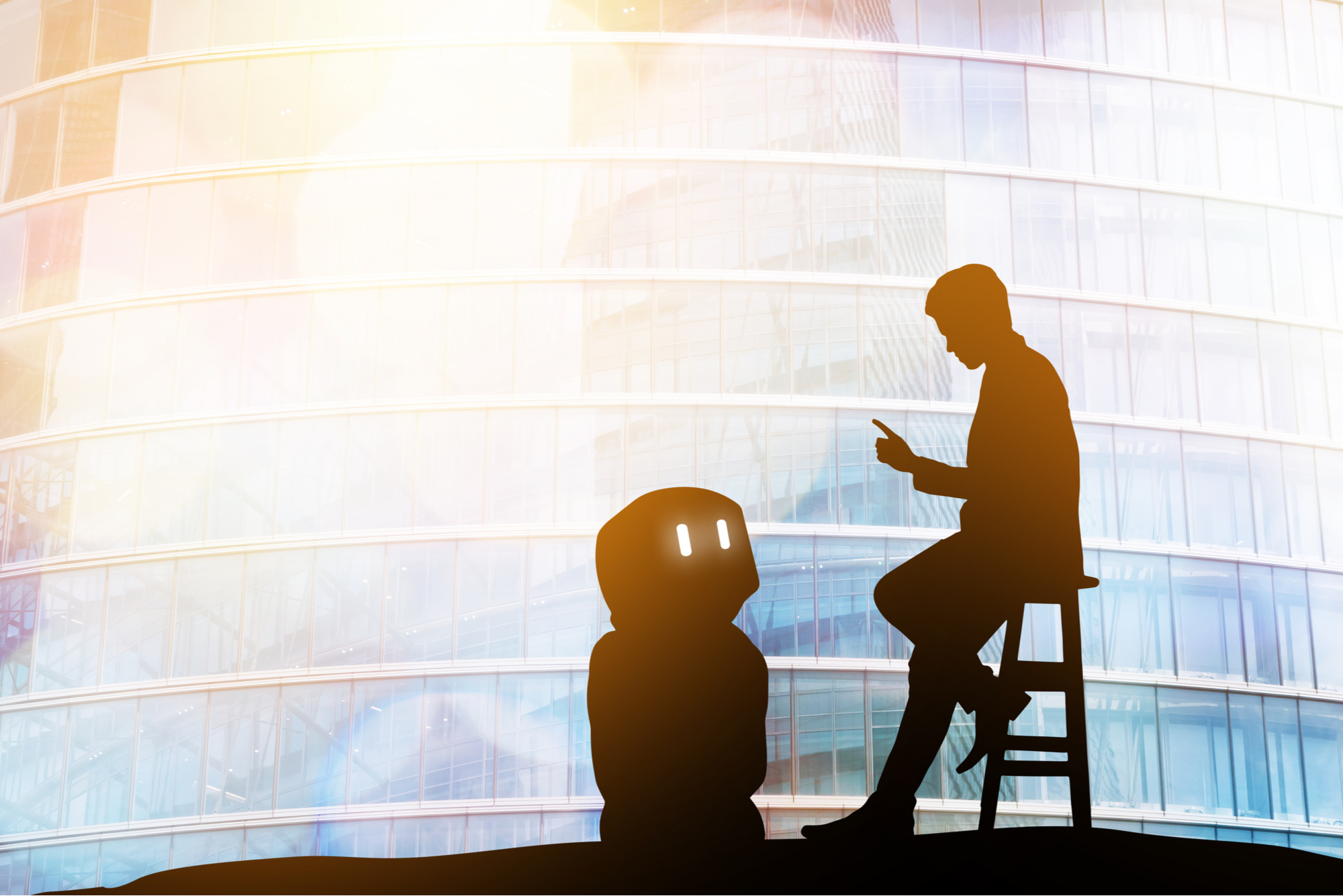 Robot and human facing each other. silhouetted against lit background