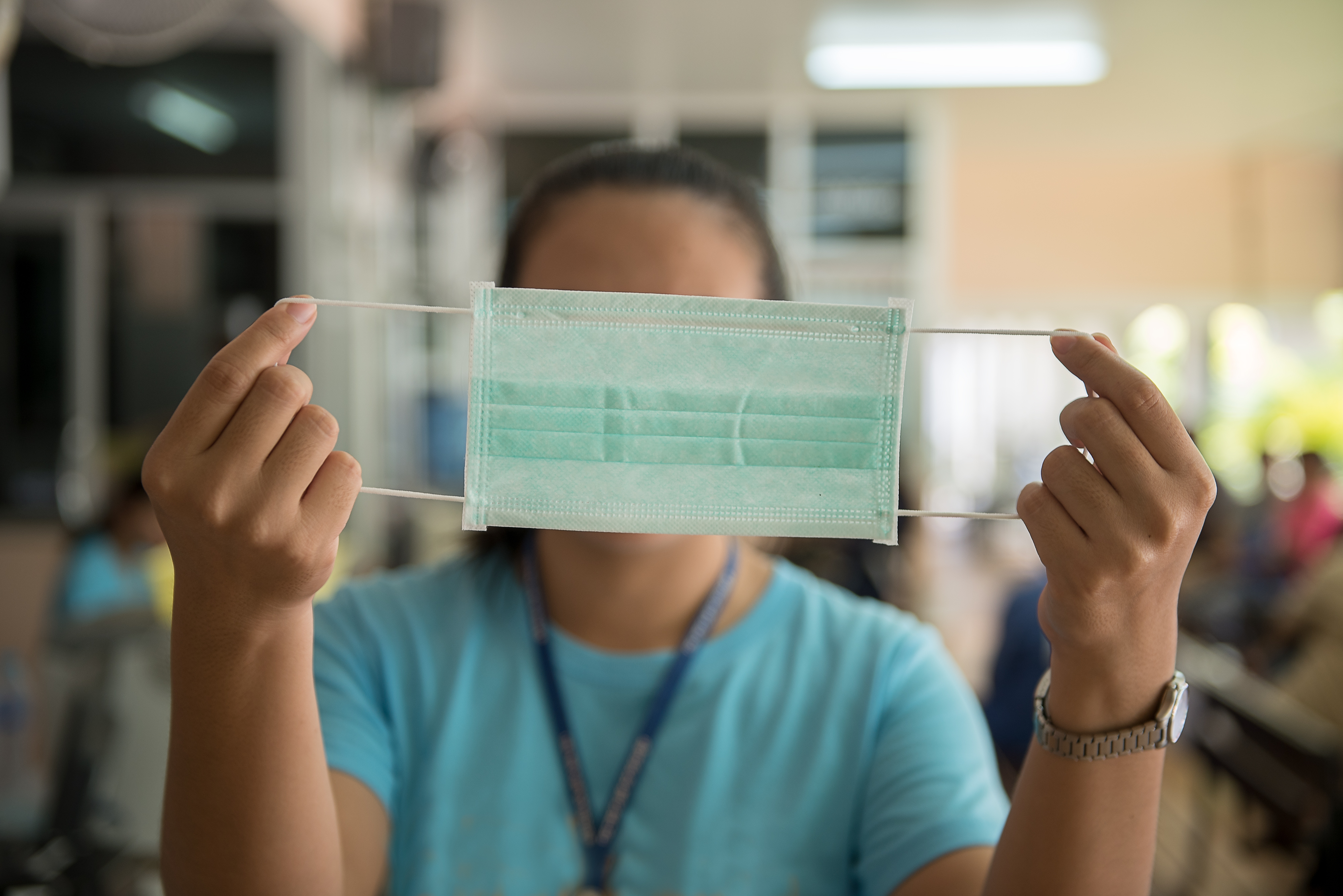 First-person perspective photograph of a health care worker holding up a mask used to prevent the spread of germs