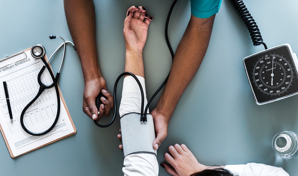 Photograph from above of a health care provider taking a patient's blood pressure.