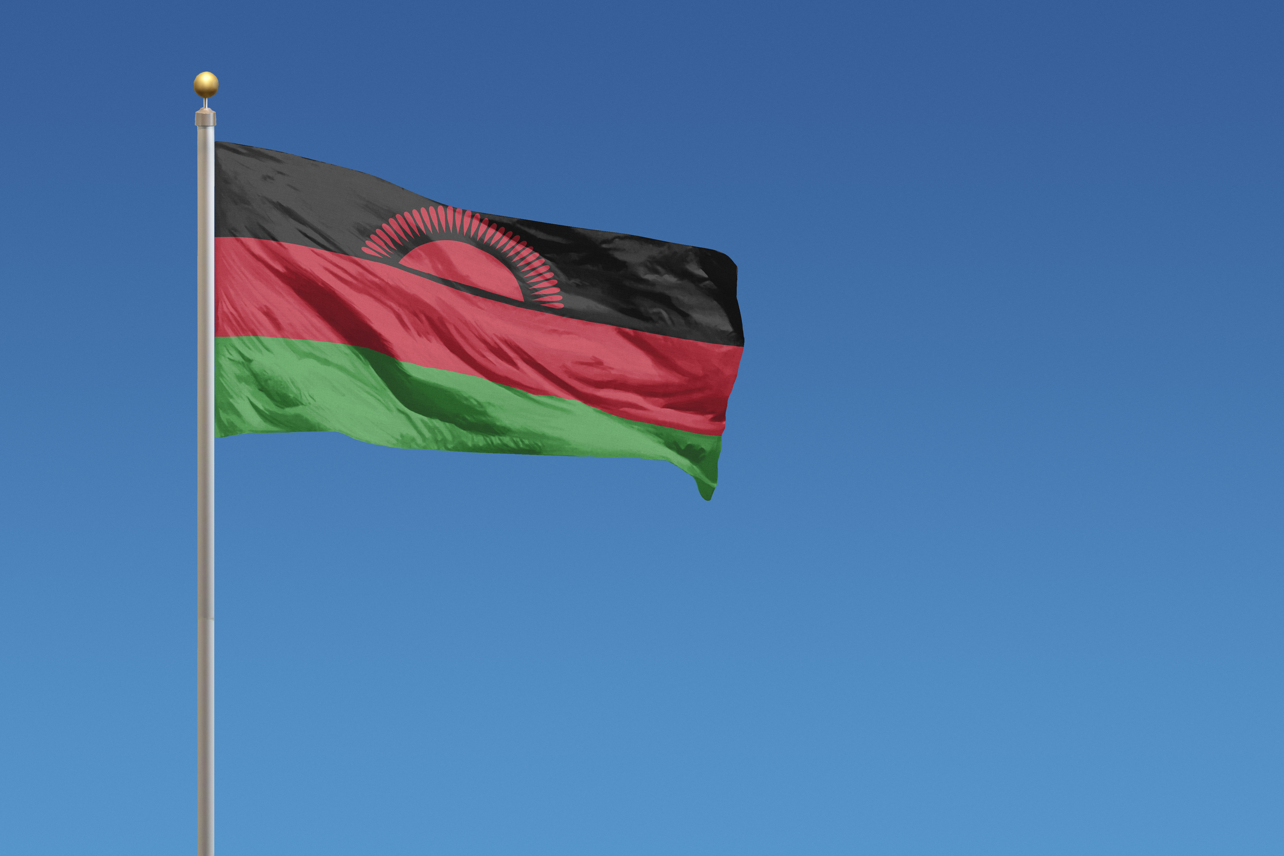 Flag of Malawi blowing in the wind in front of a clear blue sky