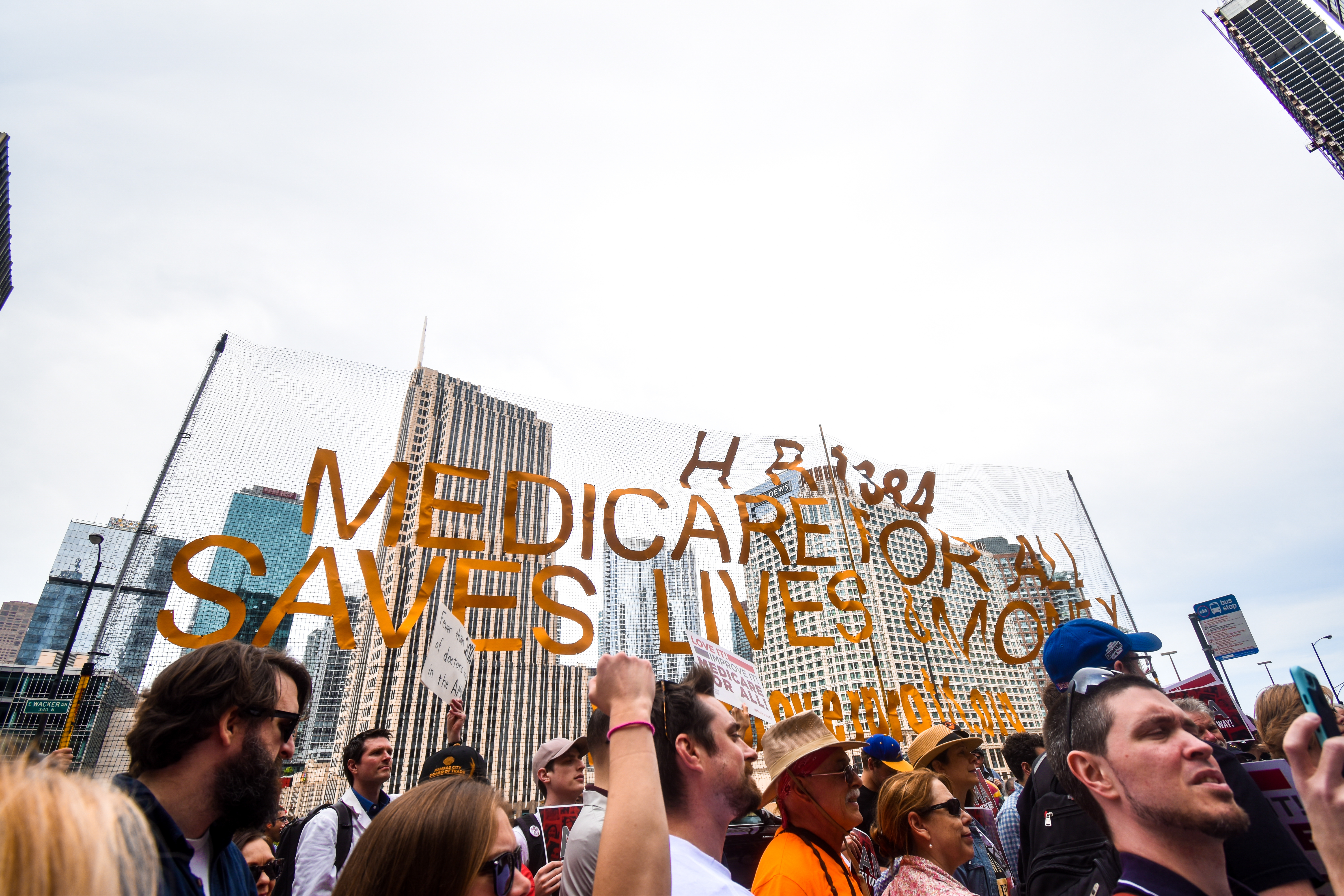 CHICAGO, ILLINOIS, USA - JUNE 8, 2019: First ever Medicare for All rally led by Bernie Sanders held in The Loop of Chicago. Crowd holds up a sign that says "Medicare for All Saves Lives".