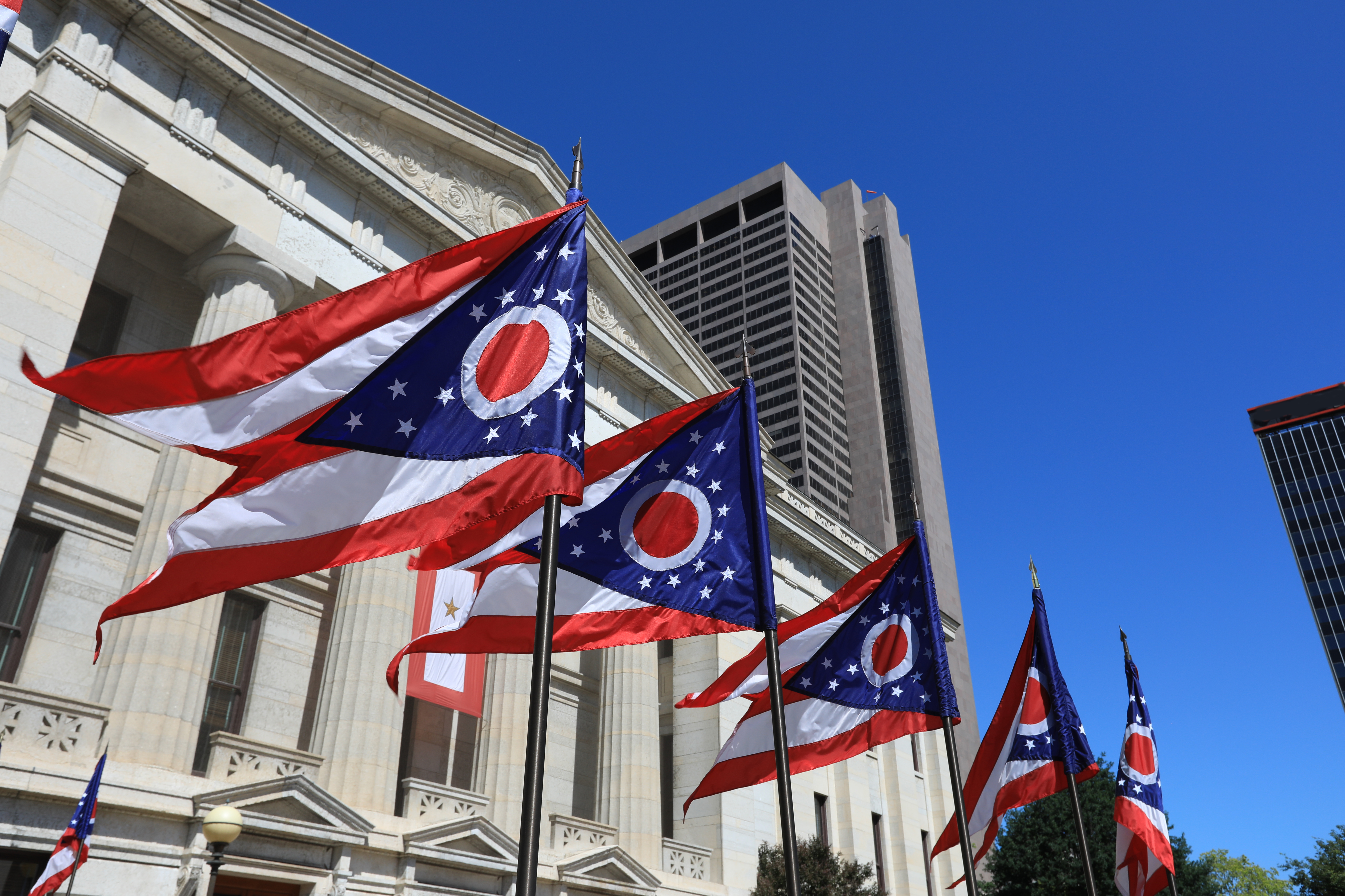 Ohio state flags waving in front of the Ohio State House