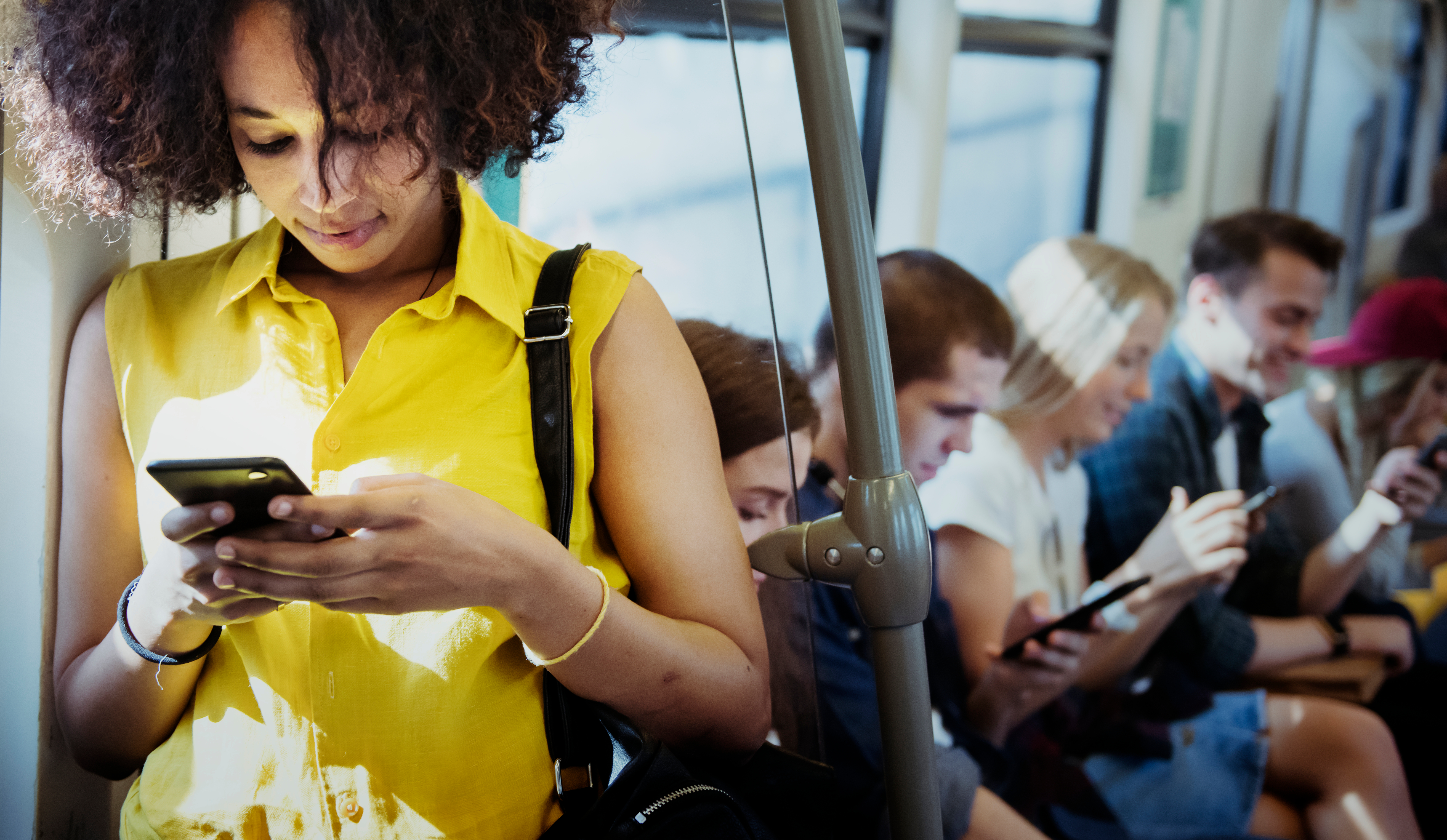 Diverse crowd of adults on a bus, all using smartphones