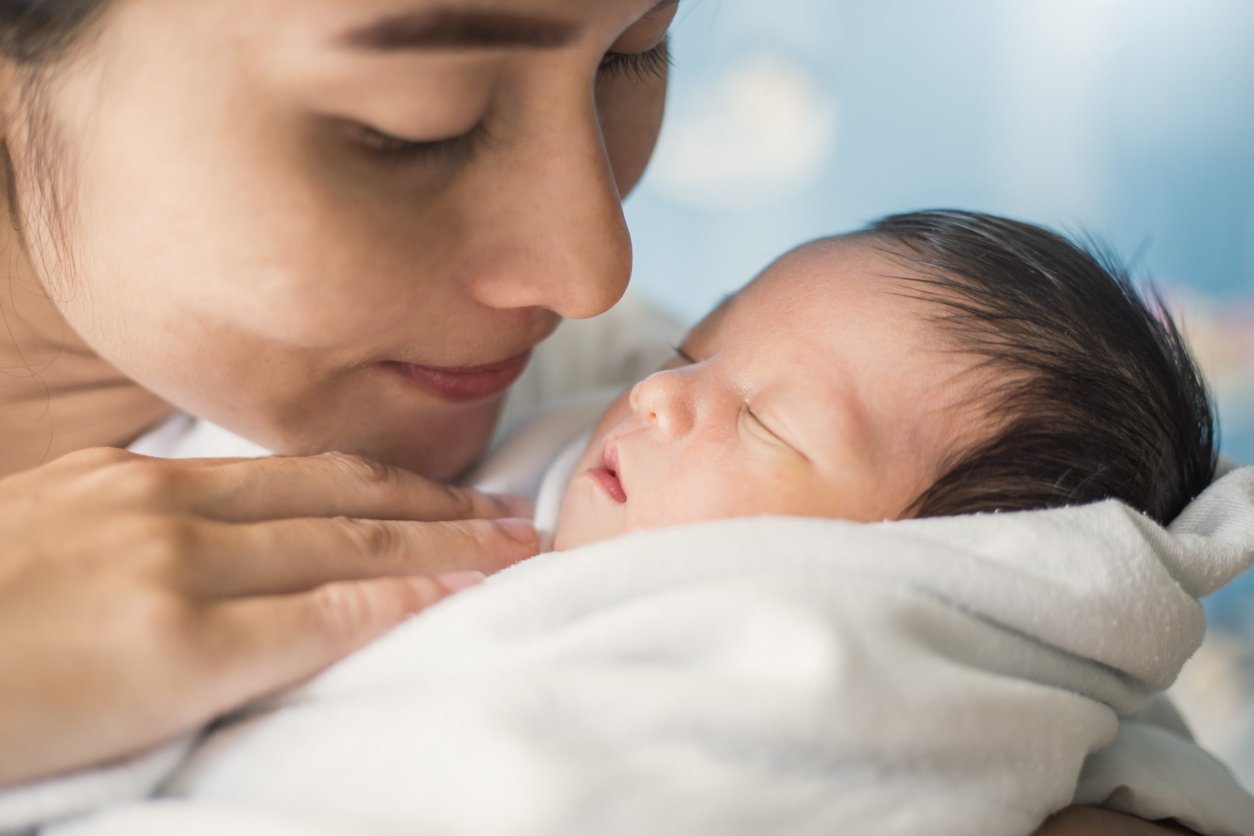 A mother holds her baby close to her chest and gazes at their face