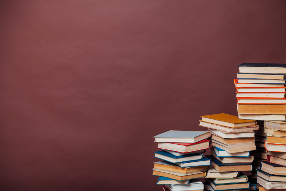 Stacks of books against a burgundy wall