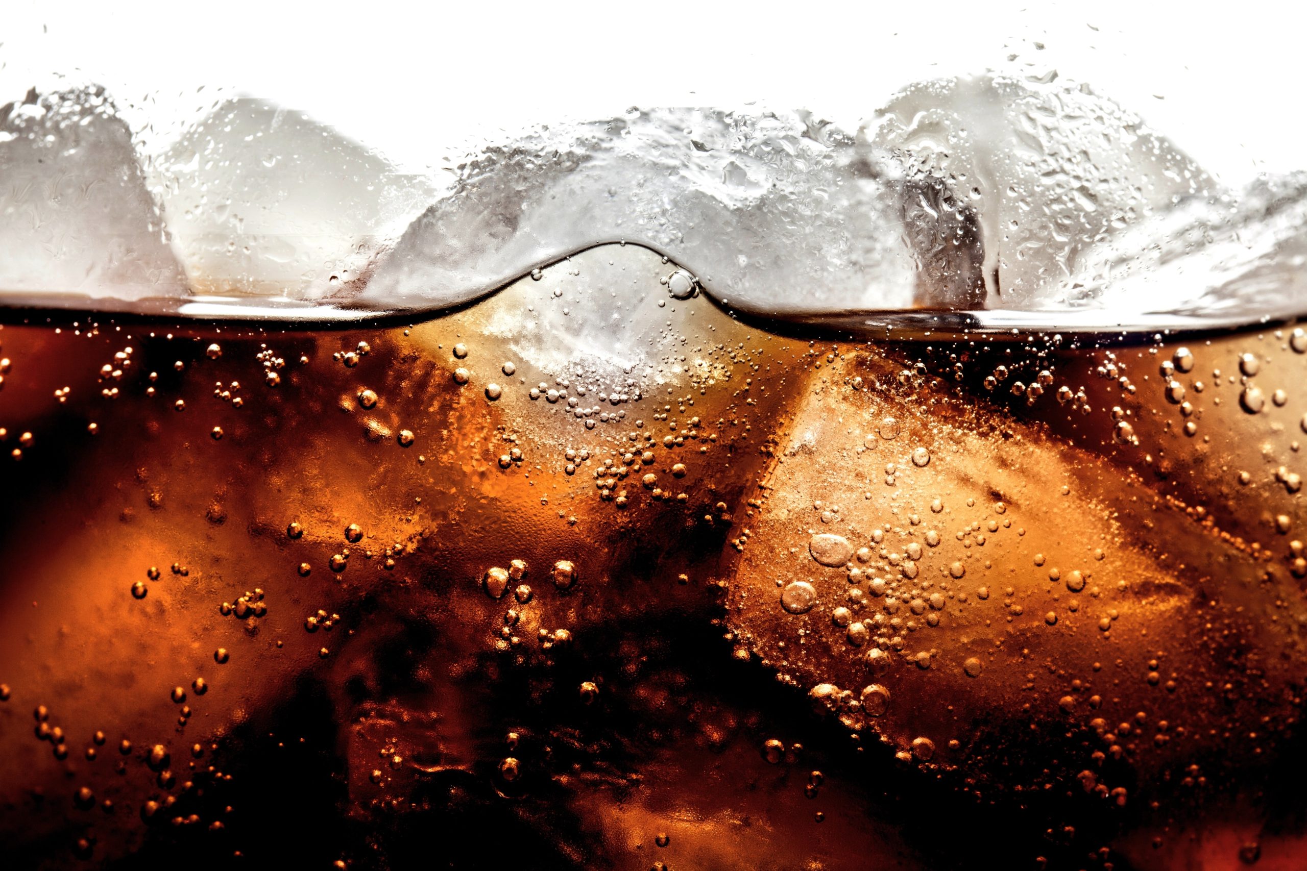 Up close details of a dark soda in ice.