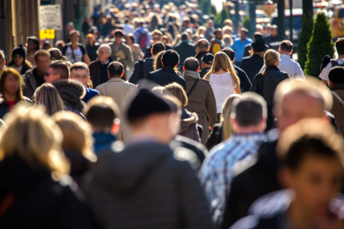 a crowd of people shuffling through a sidewalk