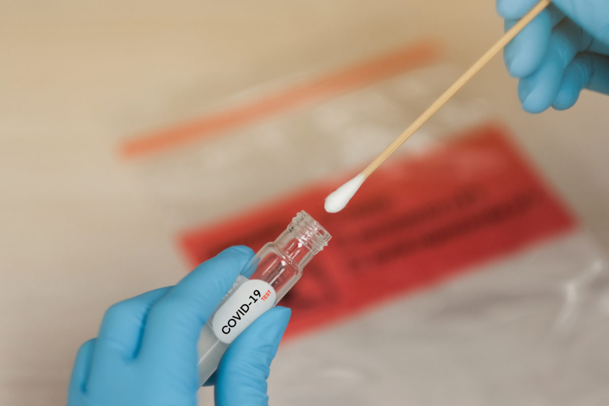 a covid 19 swab test being inserted into a vile