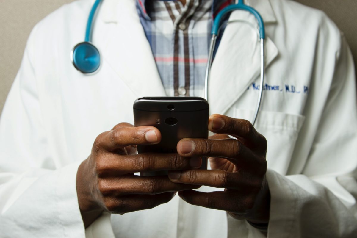 Doctor Holding Cell Phone. Cell phones and other kinds of mobile devices and communications technologies are of increasing importance in the delivery of health care. Photographer Daniel Sone.