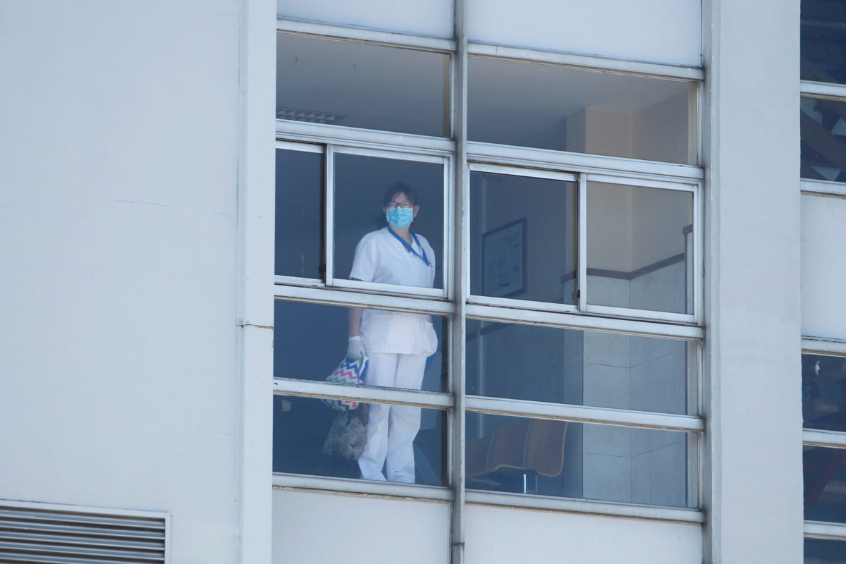 woman in PPE standing at window.