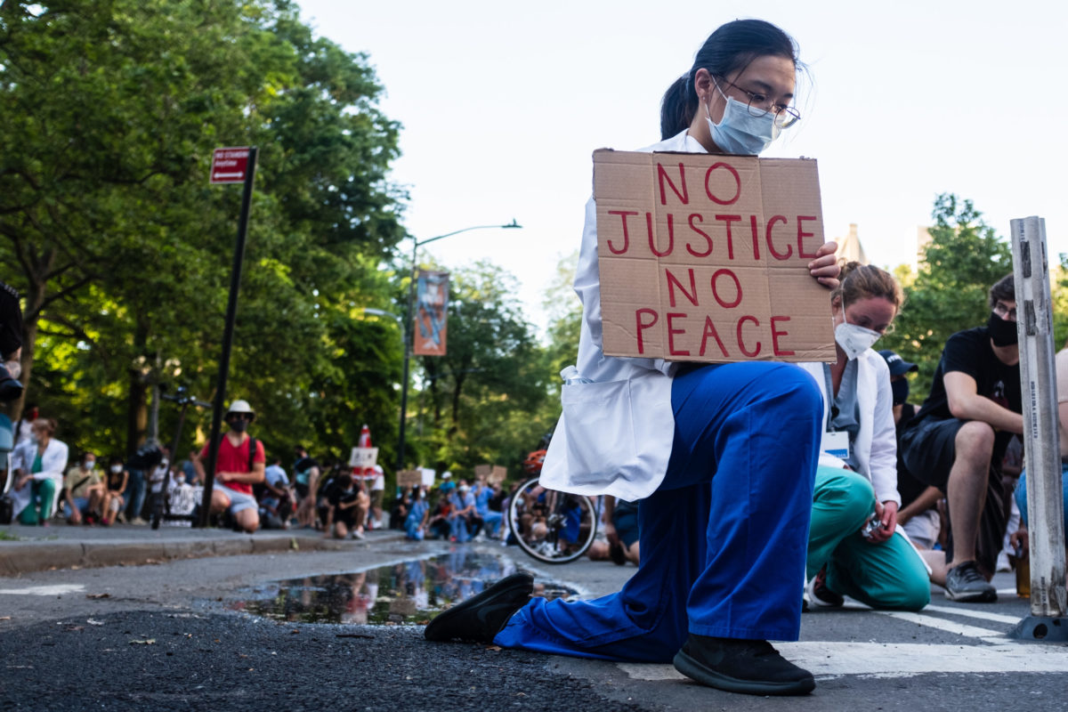 NEW YORK, NEW YORK - JUNE 06, 2020: A health care professional kneels in protest in New York City as part of the movement, 'White Coats for Black Lives,' during the COVID-19 pandemic.