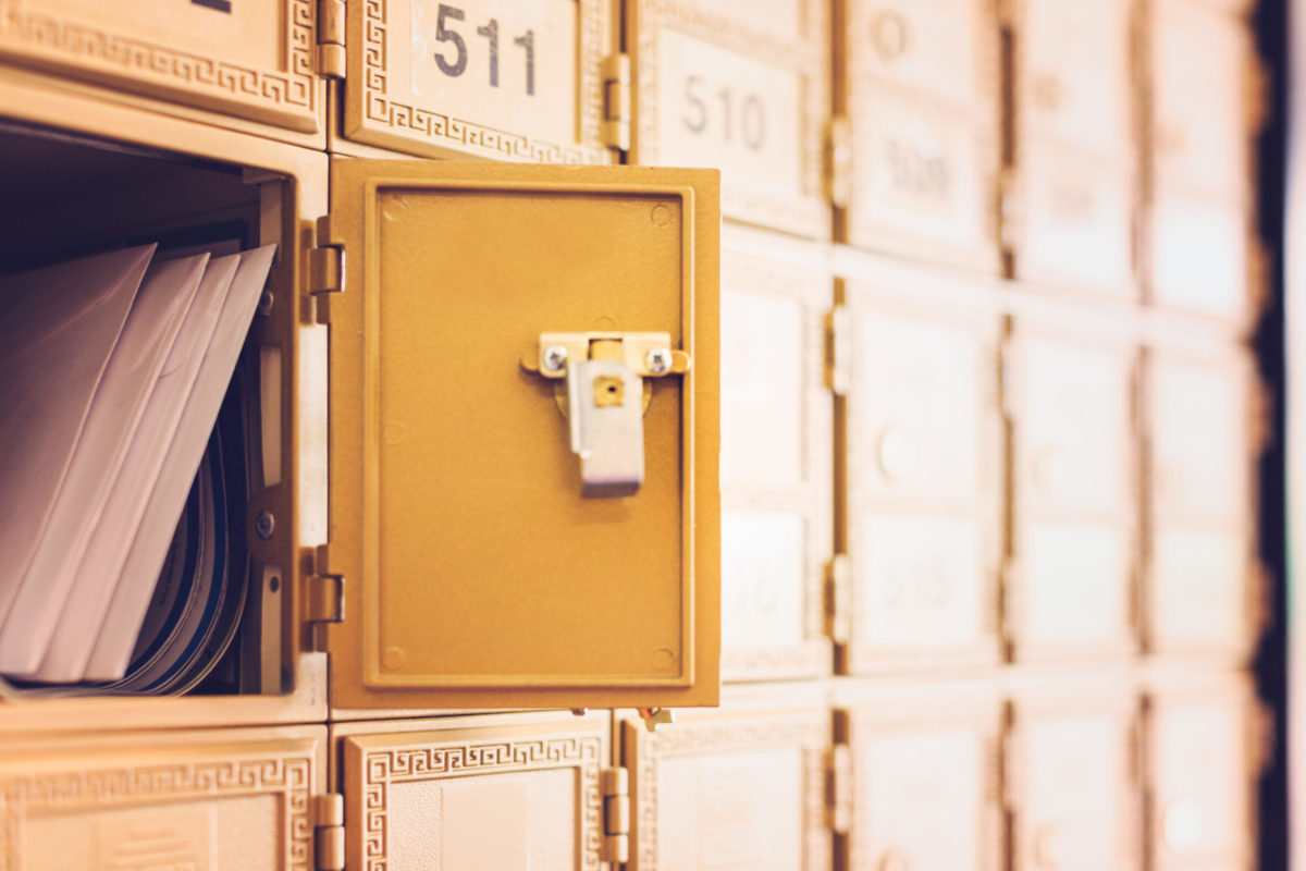 Rows of gold post office boxes with one open mail box.