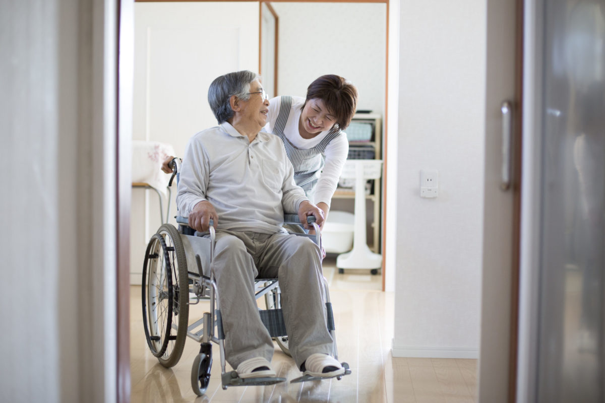 Woman helping man in wheelchair at home.