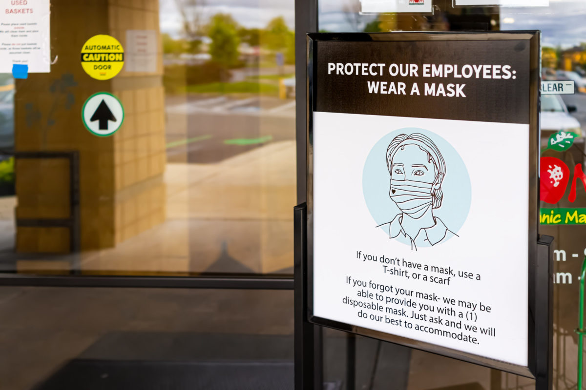 Herndon, USA - April 27, 2020: Virginia Fairfax County building exterior sign entrance to Mom's Organic Market store with request to wear face mask due to covid-19 pandemic.