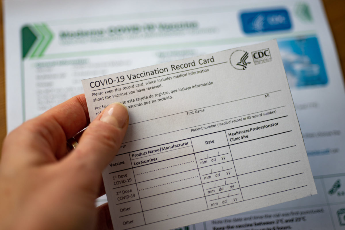 Washington, DC, USA - Closeup view of December, 23, 2020: COVID-19 Vaccination Record Card by CDC on blurred documents background.