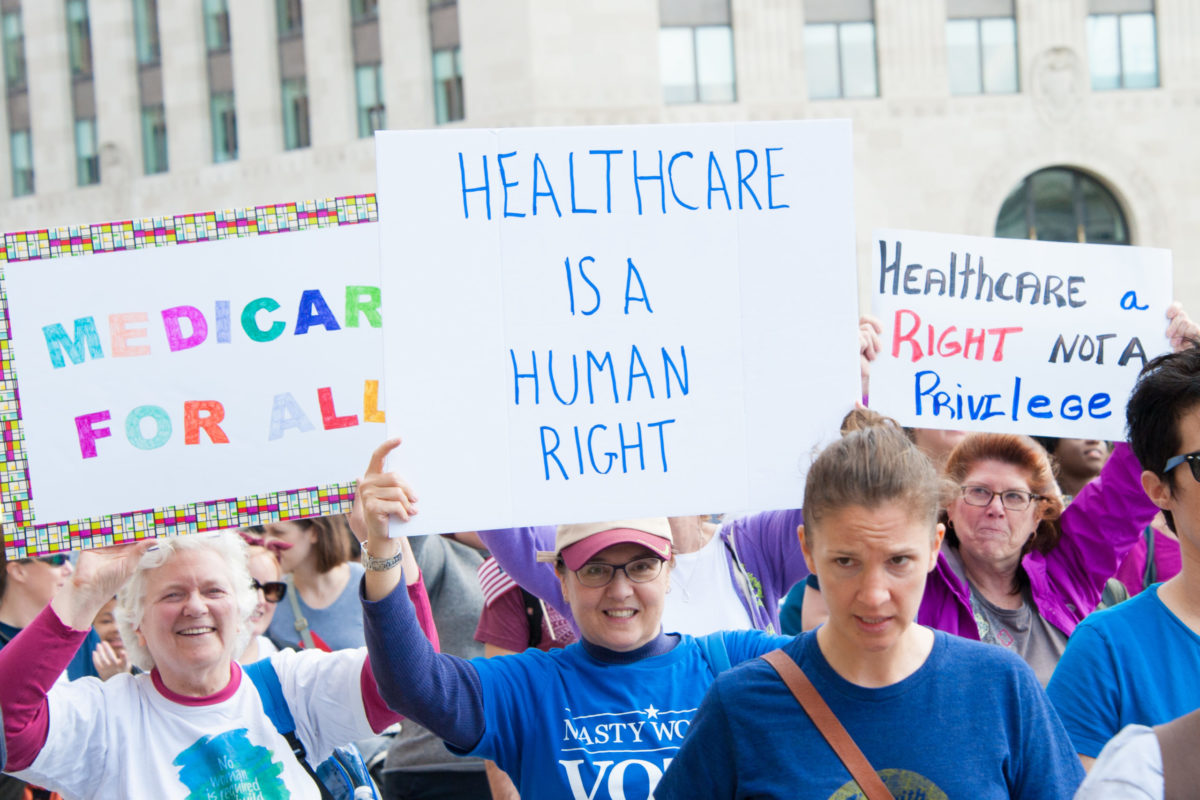 People protesting with signs that say "healthcare is a human right" and "medicare for all."