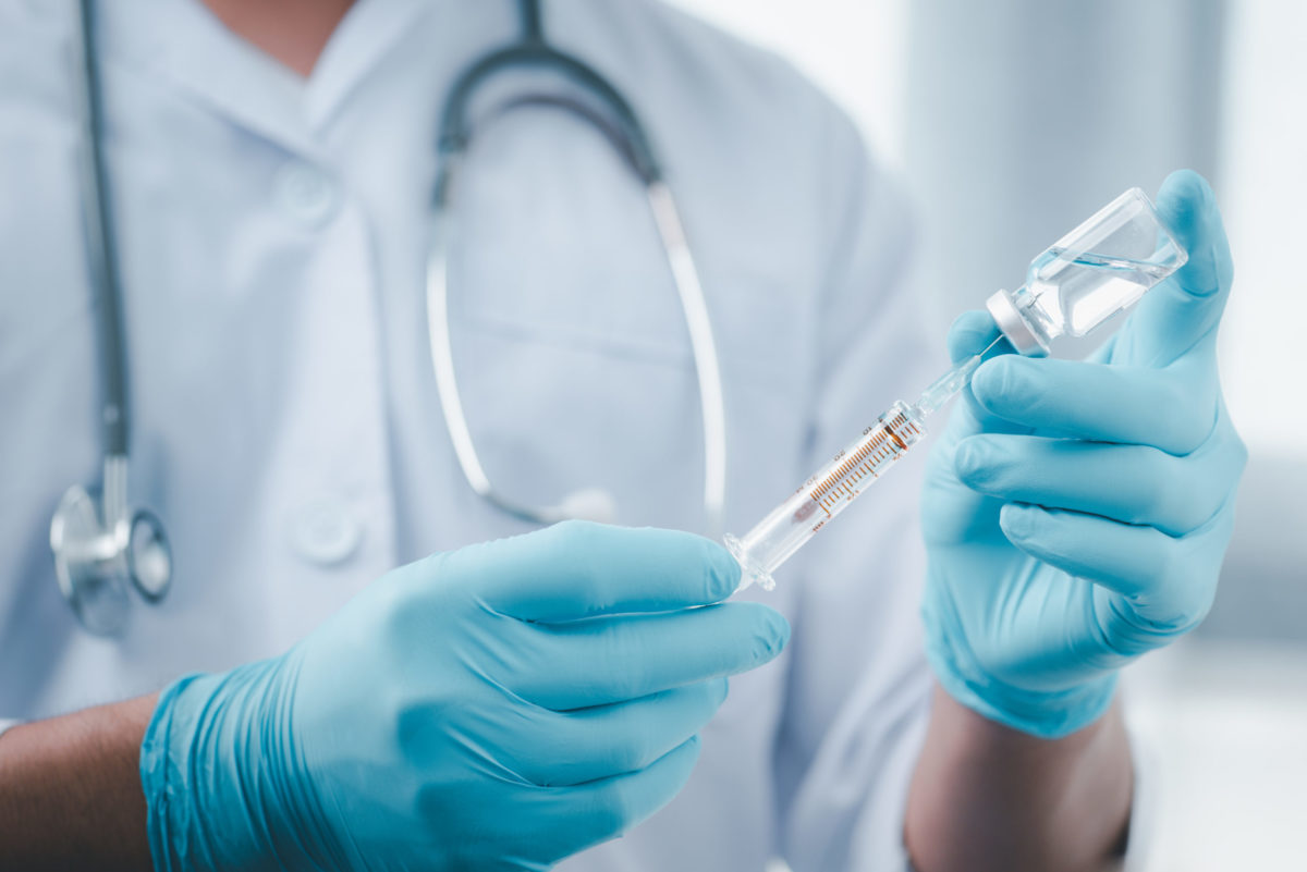 Person filling syringe from vial.