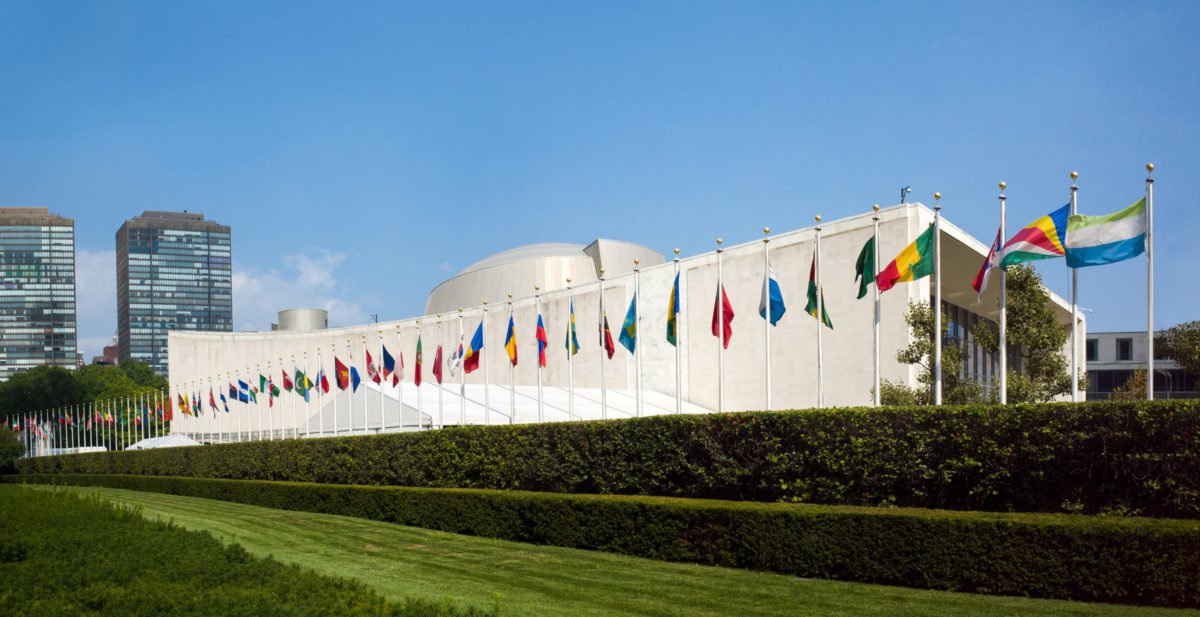 UN United Nations general assembly building with world flags flying in front - First Avenue, New York City, NY, USA