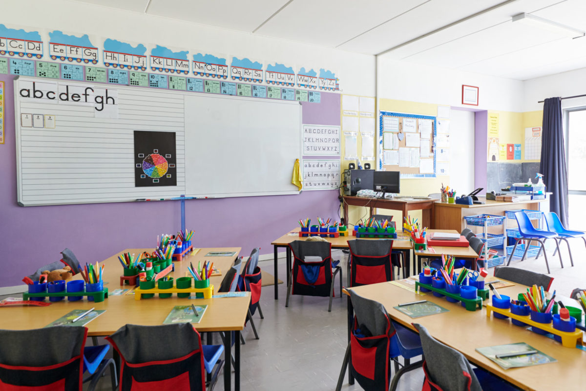 Empty Classroom In Elementary School With Whiteboard And Desks.