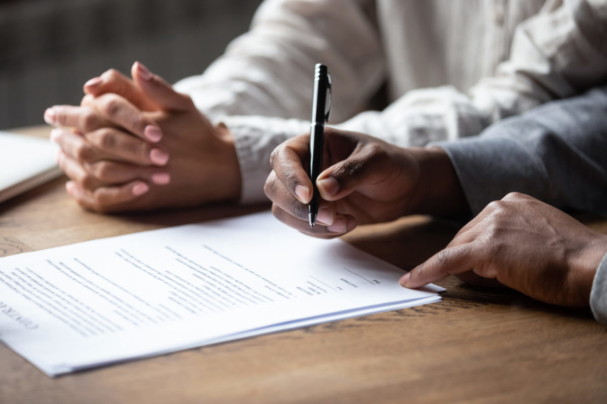 close up of hands signing contract.