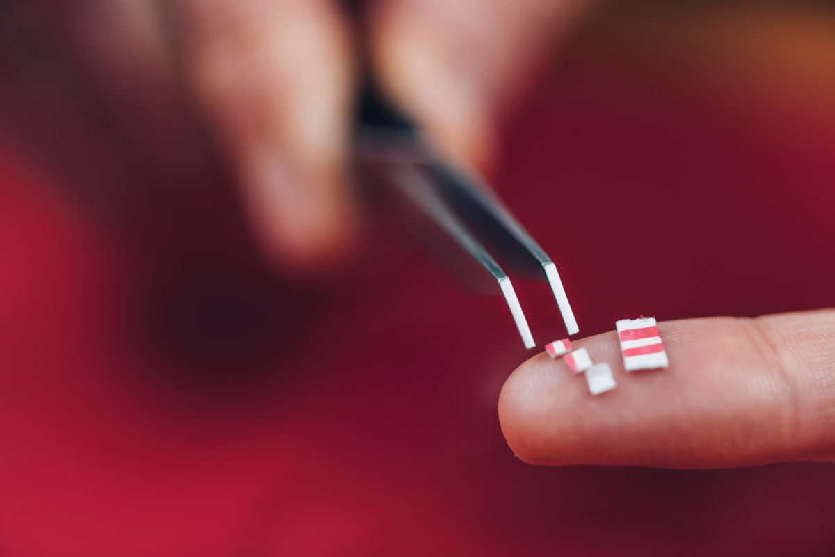 LSD Microdosing. Small or micro doses of LSD drug cut from a tab, presented on a finger.