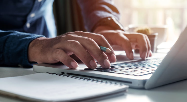 Businessman's hands typing on laptop keyboard in morning light