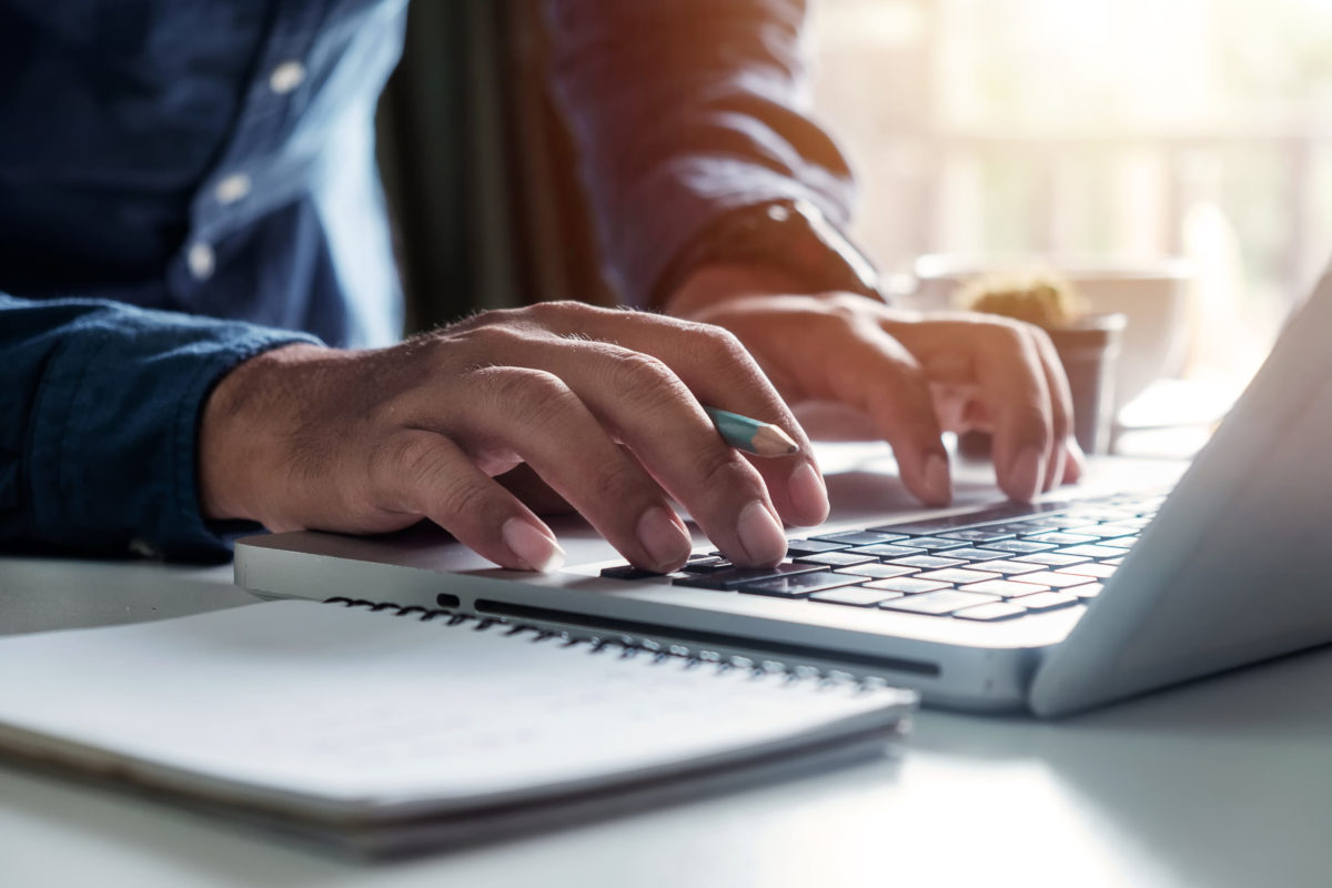 Businessman's hands typing on laptop keyboard in morning light