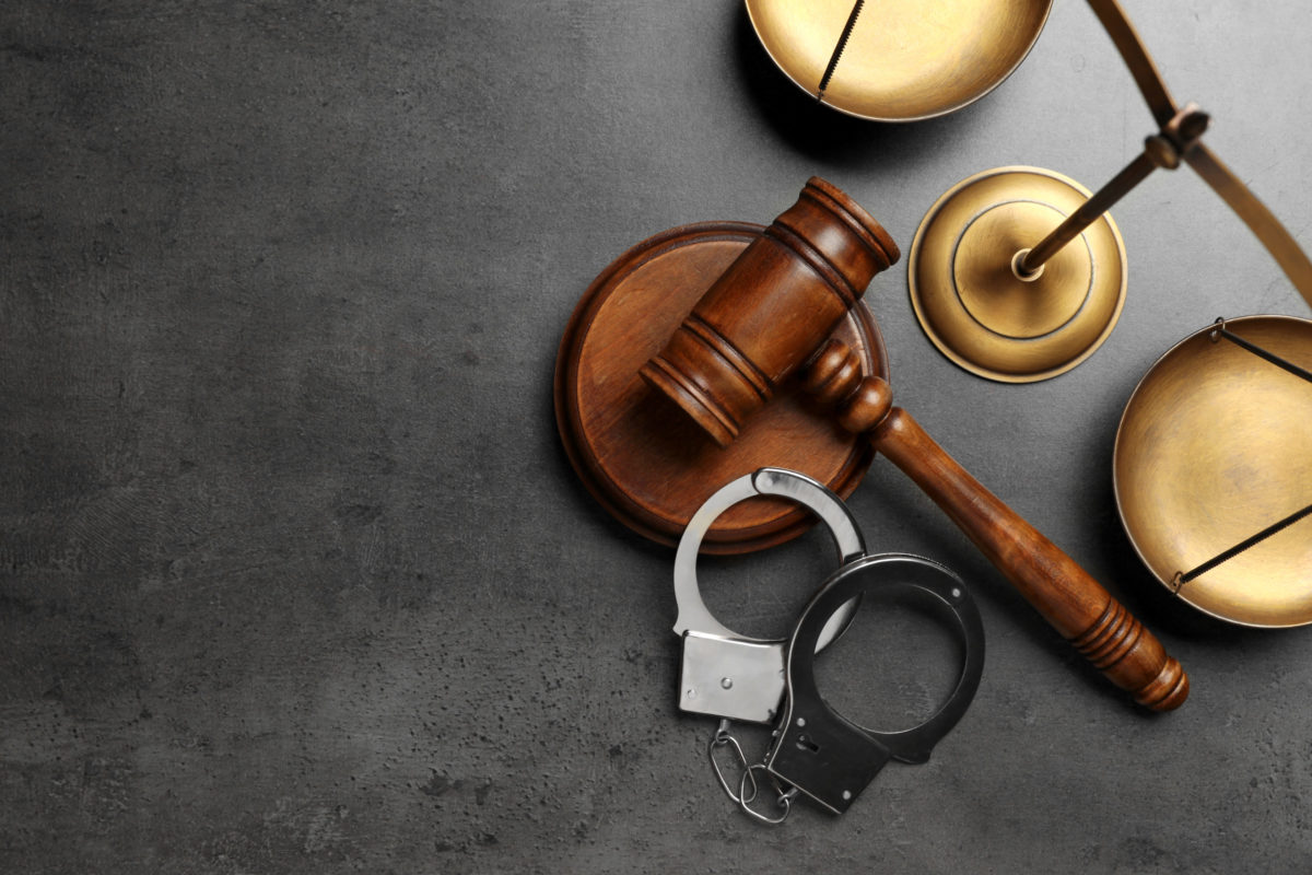 Judge's gavel, handcuffs and scales on grey background, flat lay with space for text. Criminal law concept.