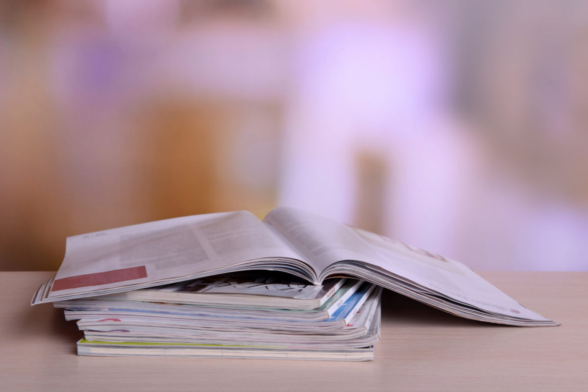 Magazines on wooden table on bright background.