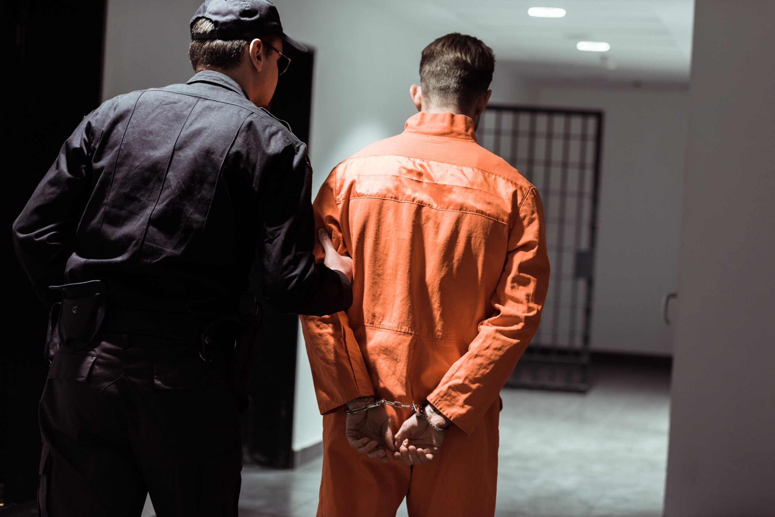 Bill of Health - man in prison orange is lead out by guard, decarceration