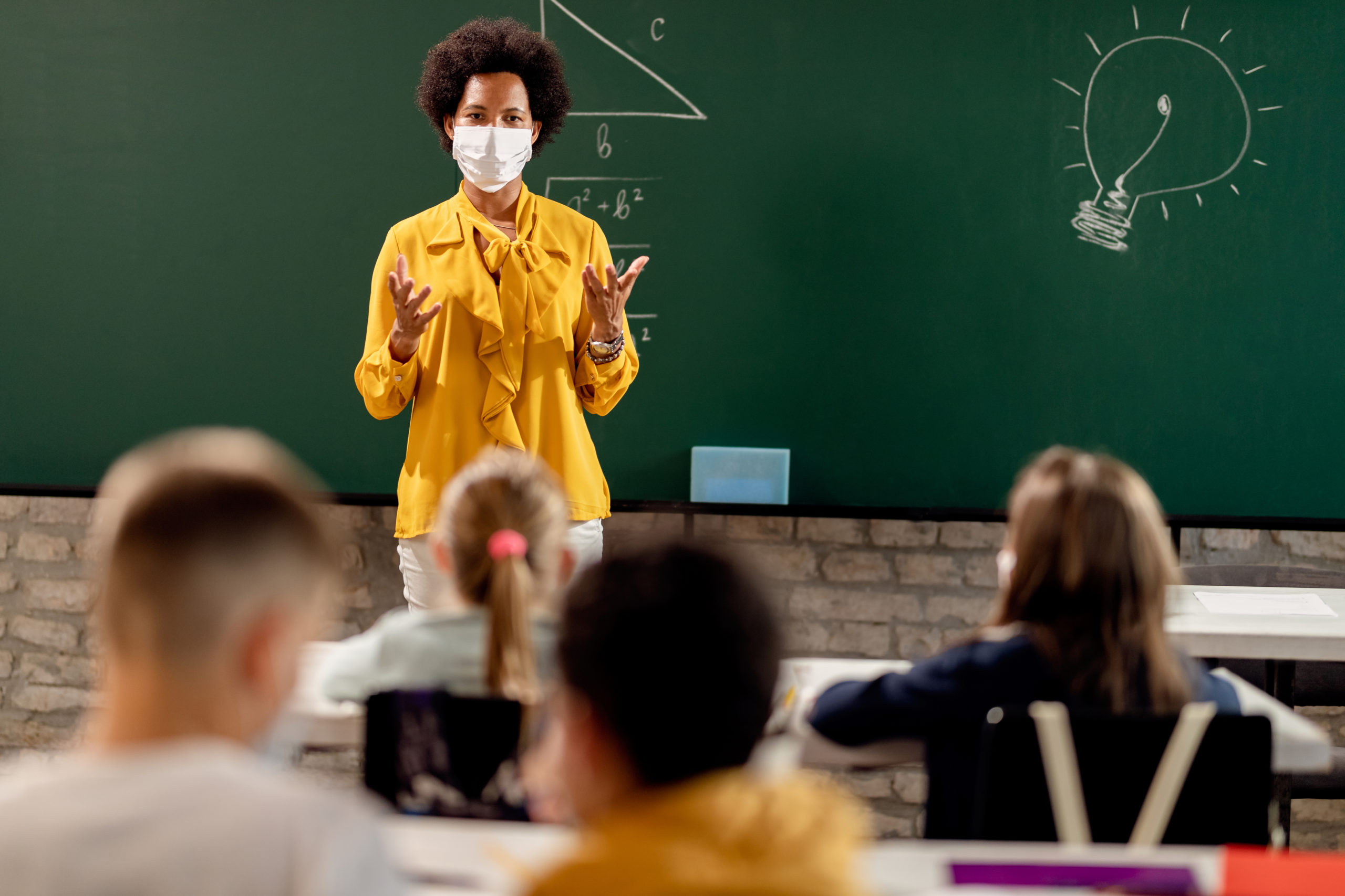 Bill of Health - teacher teaches math while wearing a mask, teacher in mask in front of blackboard, teachers' rights in the pandemic