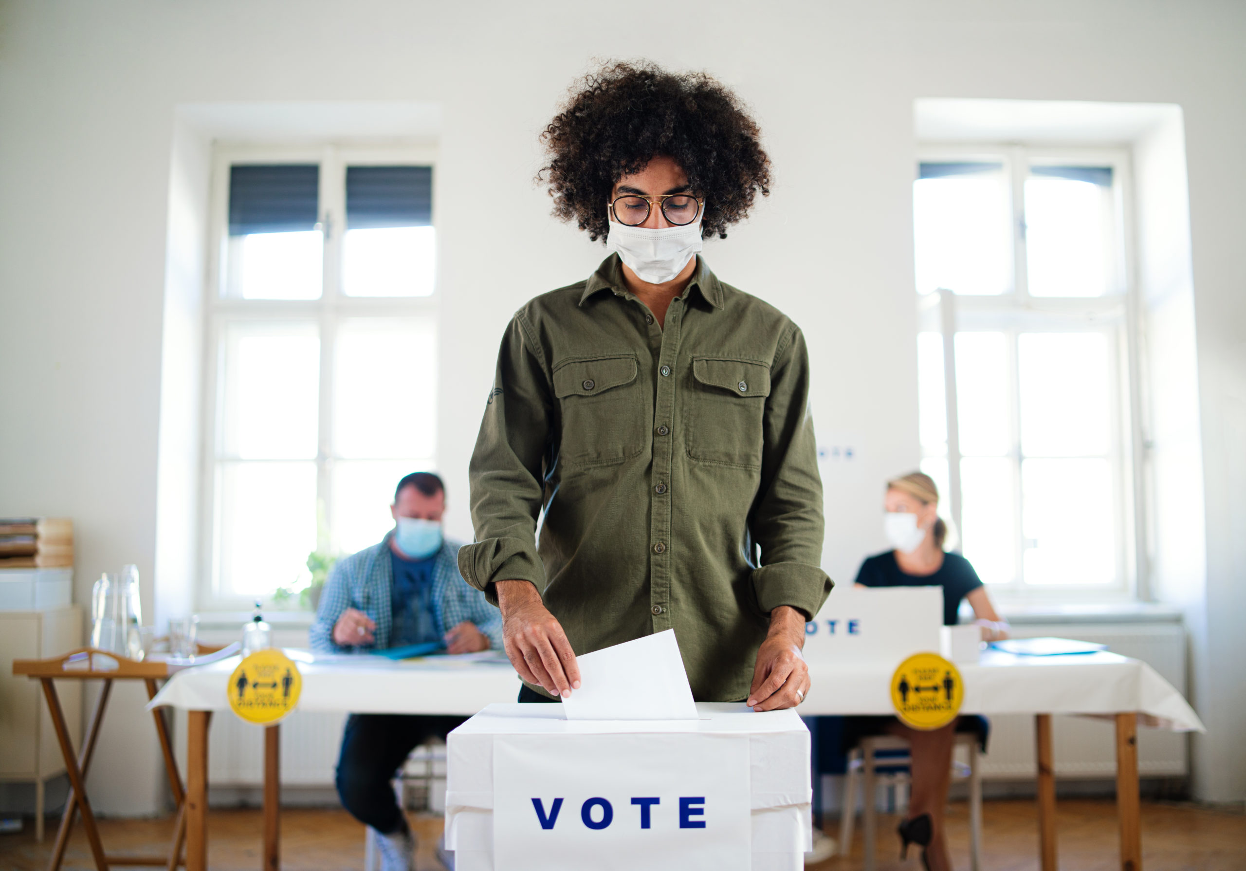 Bill of Health - young Black man casting his vote with mask one, pandemic elections