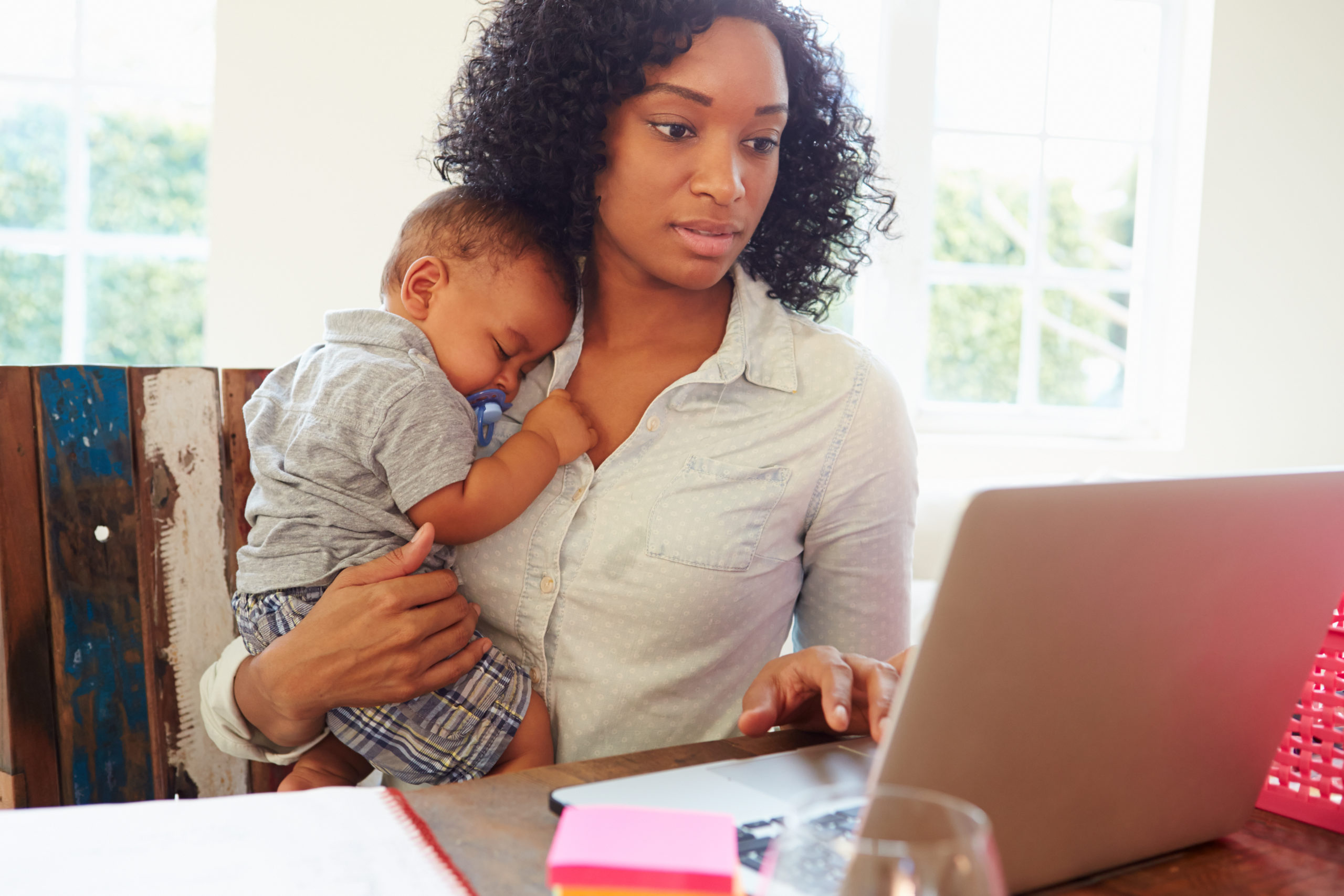 Bill of Health - young mother with her baby working on a computer, caregiver, work from home