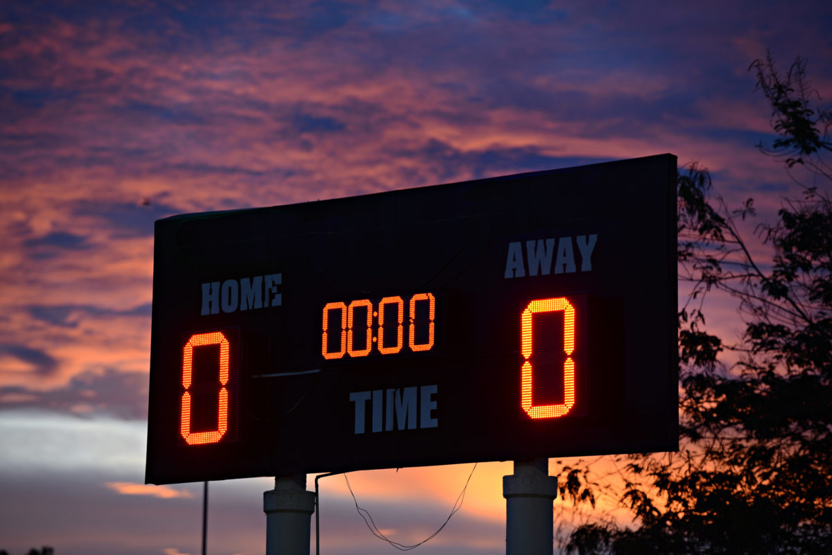 scoreboard with home and guests written on it at sunset time.