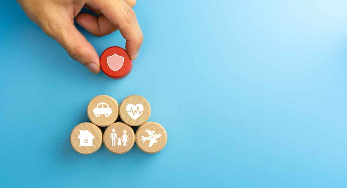 Insurance concept. Wooden blocks with insurance icons. family, life, car, travel, health and house insurance icons on blue background.