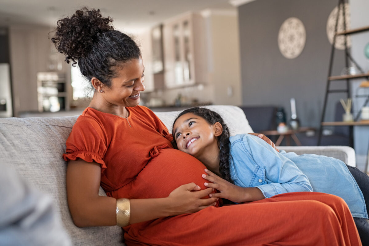 Child smiles at pregnant mother.