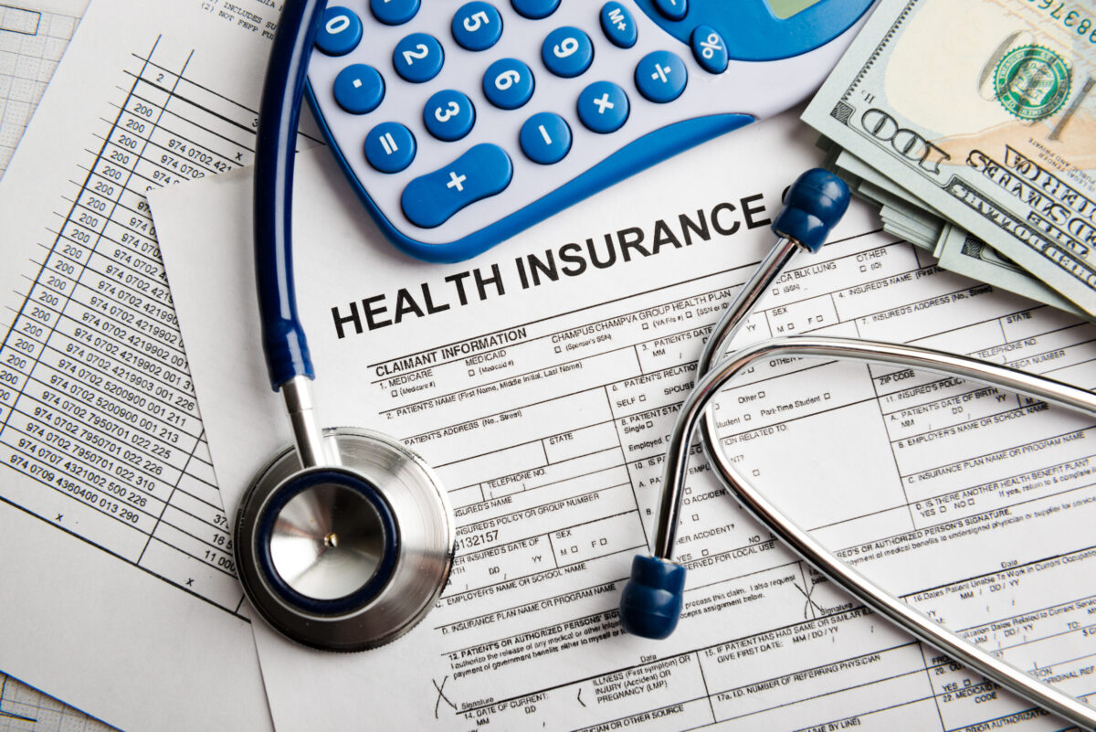 Health insurance application form with money, calculator, and stethoscope.