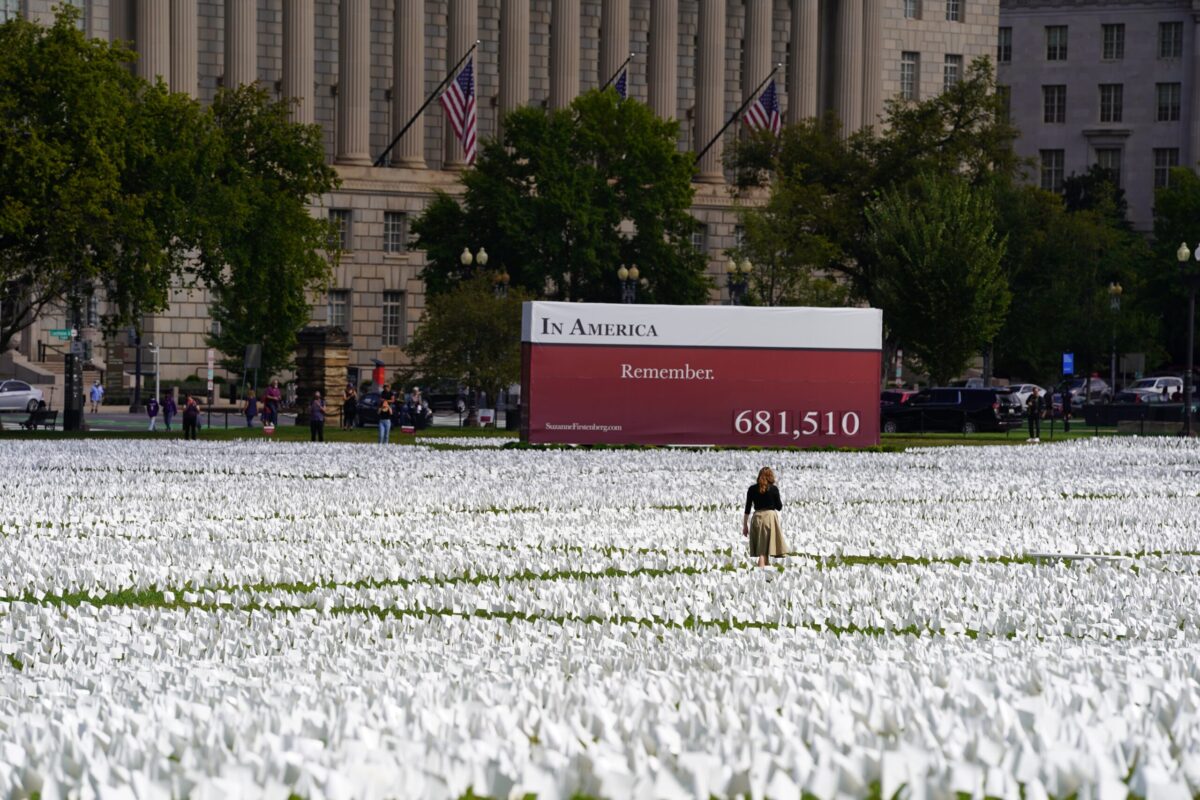 Washington, DC – September 23, 2021: A person walks among the over 681,000 memorial white flags dedicated to each of the COVID Pandemic victims at the National Mall.