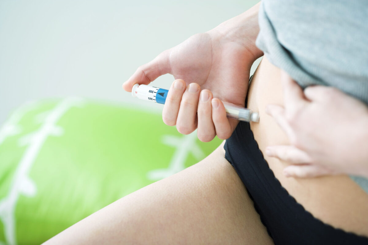 Woman injecting hormones into her abdomen to stimulate follicles for IVF.