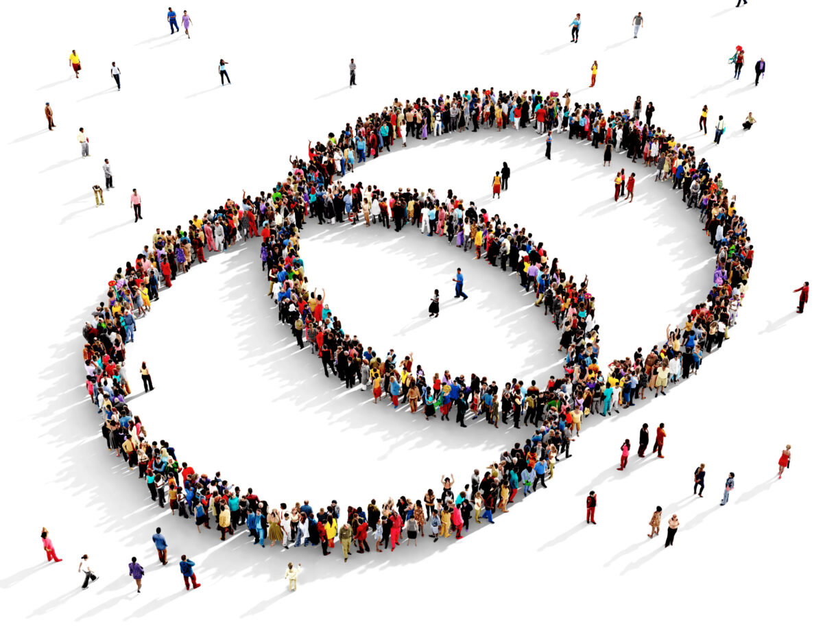 Large and diverse group of people seen from above gathered together in the shape of two intersecting circles.