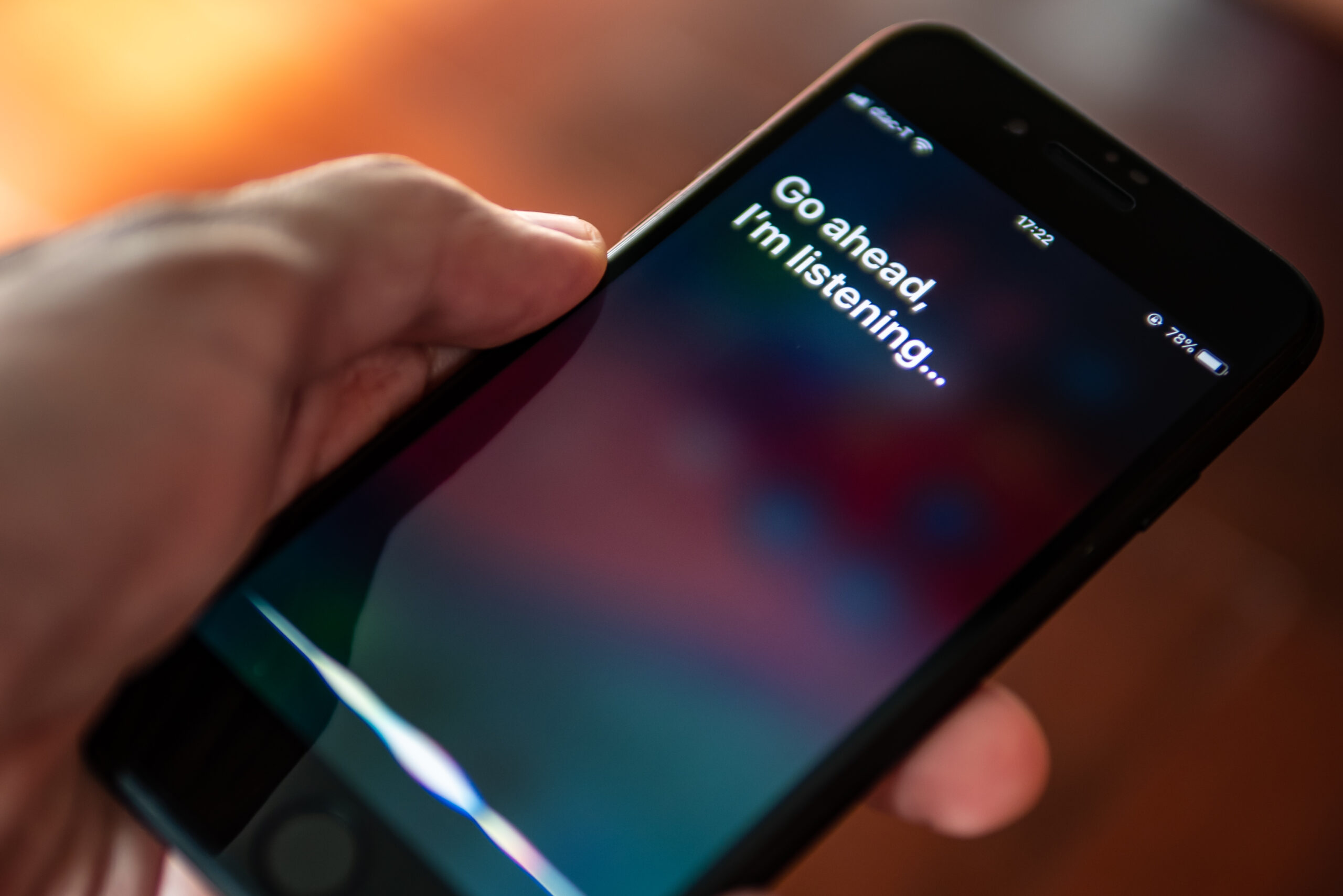 Siri, Apple's voice-activated digital assistant, tells iPhone user, "Go ahead, I'm listening," which also displays as text on the screen.