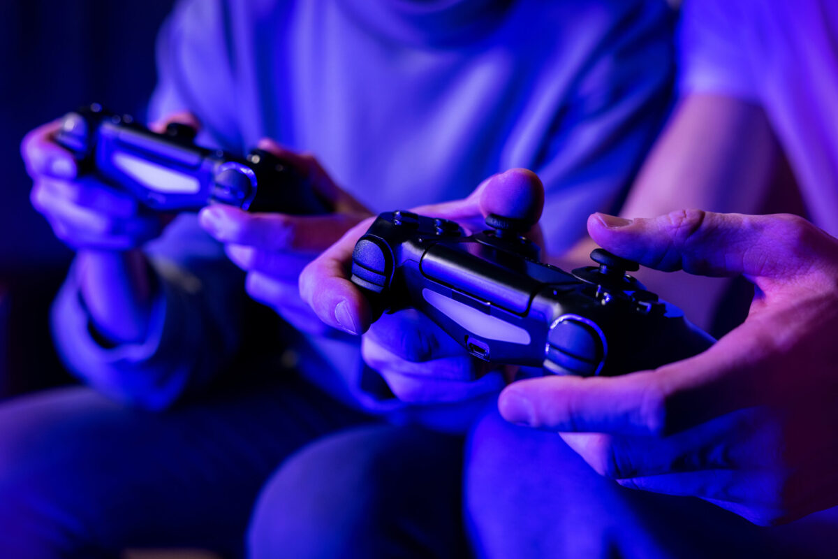 friends playing console video games. controller in hands closeup. neon lights.